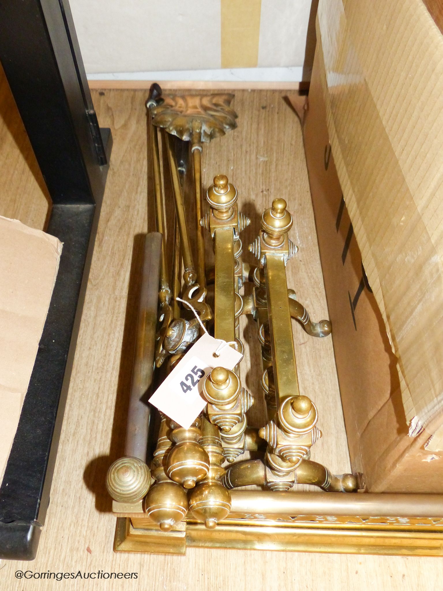 A brass fender, pair of fire dogs and set of three brass fire irons